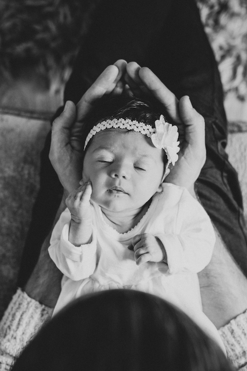 Black and white photo of newborn baby being held in dads hands | Newborn And Family Photography Portfolio | Fine art new baby portraits Buckinghamshire