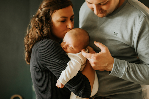 Newborn being held and kissed by mummy and daddy | Lifestyle Photoshoot at Home