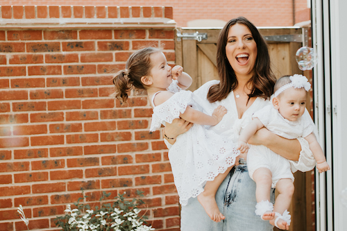 Brunette mum laughing whilst holding her two daughters. Newborn, Wedding and Family Portfolio | Amy Foster Photography