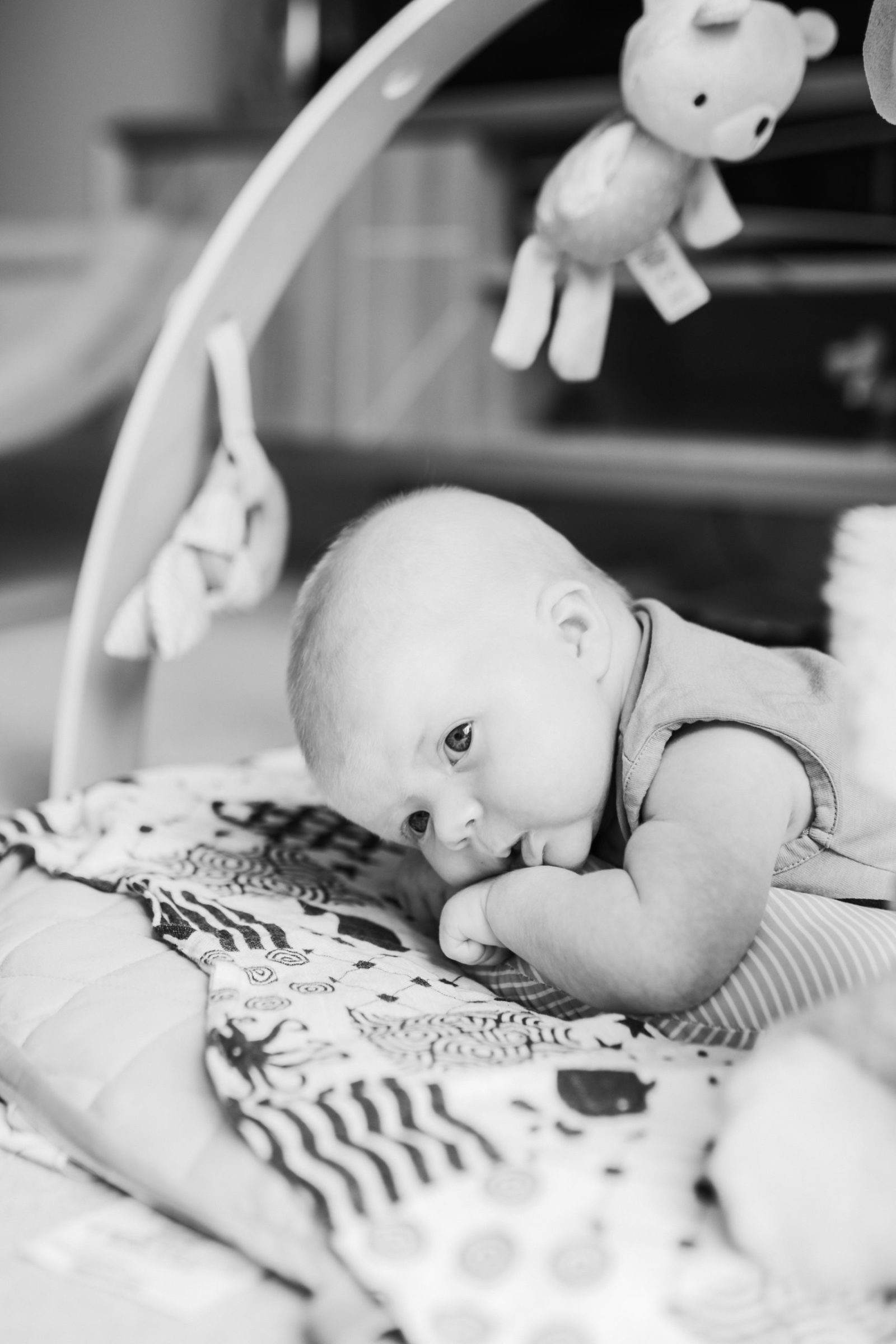 Black and white image of baby on his front on baby mat. 