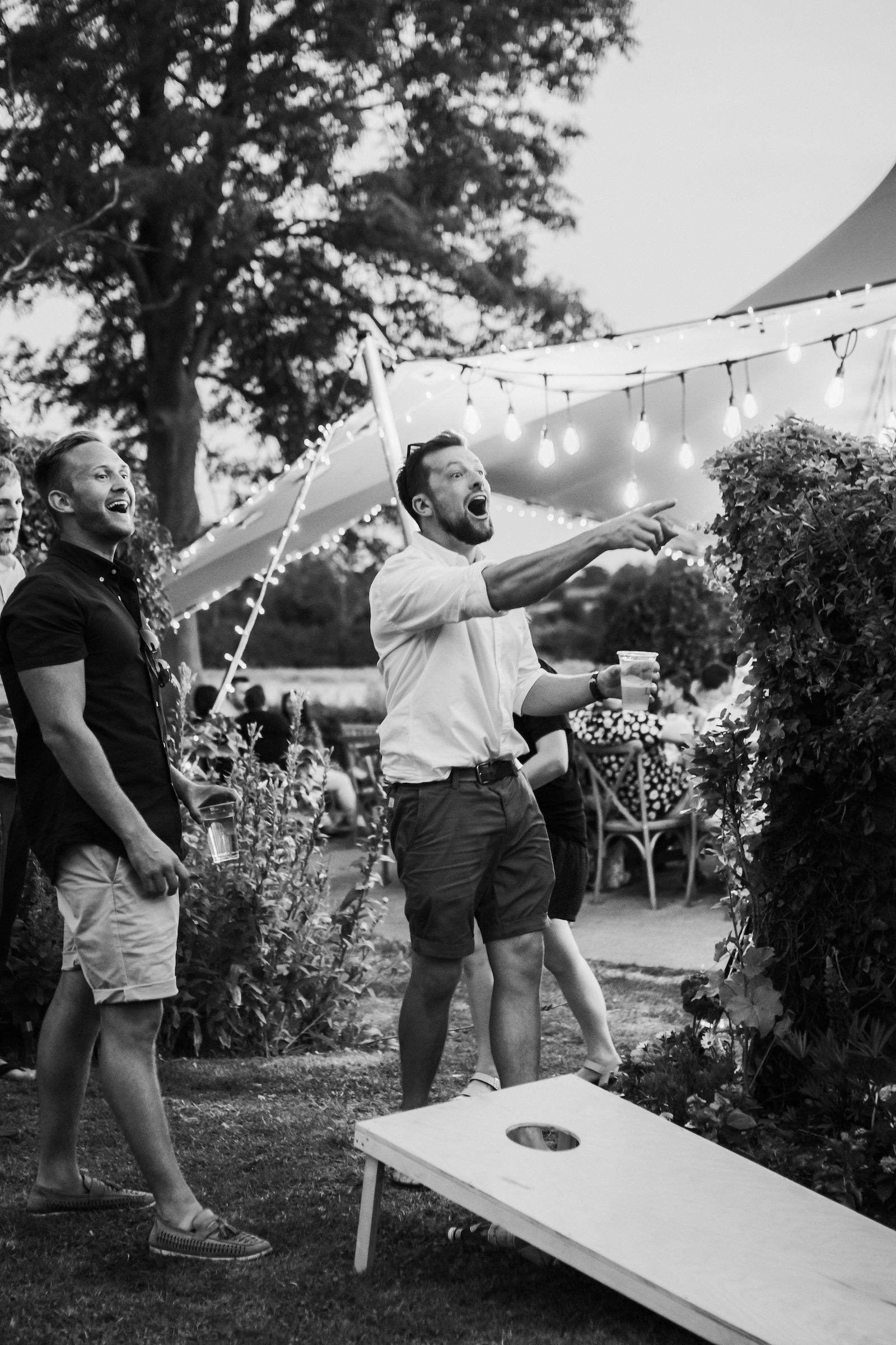 Black and white image of two men playing garden game at wedding