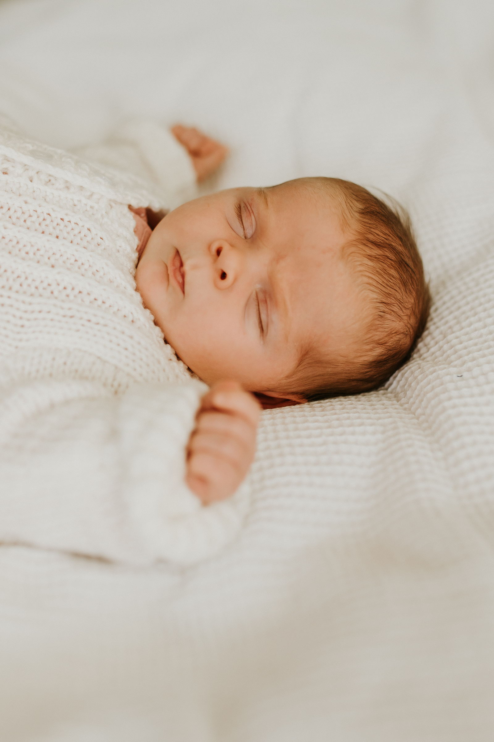 Newborn baby on white bed sheets